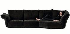 a woman sitting on top of a black couch