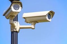 two security cameras mounted on the side of a metal pole against a blue sky background