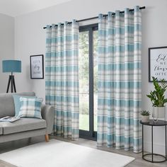 a living room with a couch, chair and window covered in blue plaid curtain panels