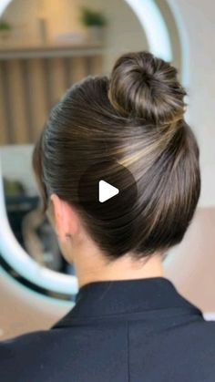 a woman with her hair in a bun is looking at the mirror and has an ad for