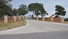 a gated entrance to a ranch with wooden posts and gates on both sides, leading into the distance