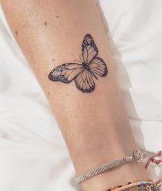 a woman's arm with a small butterfly tattoo on the left side of her wrist