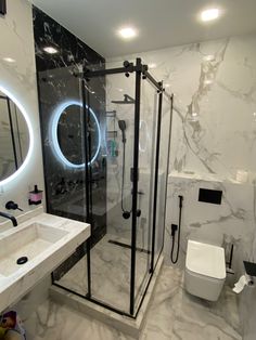 a bathroom with marble walls and flooring has a round mirror above the shower stall