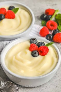 two white bowls filled with pudding and berries