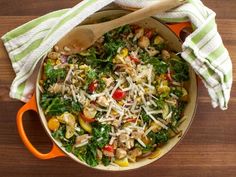 a pan filled with vegetables and cheese on top of a wooden table next to a towel