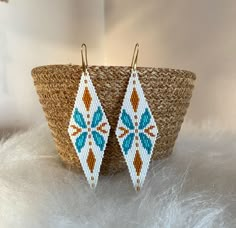 the beaded earrings are on display in front of a basket with white furnishing