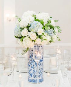 a blue and white vase filled with flowers sitting on top of a dining room table