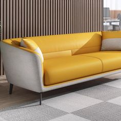 a yellow leather couch sitting in front of a wooden wall with two chairs and a table