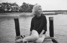 a woman sitting on the end of a dock