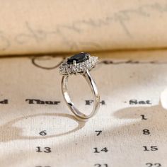 a diamond and black stone ring sitting on top of an open book