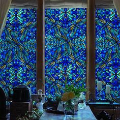 a room with three large stained glass windows in the center and two vases on the table