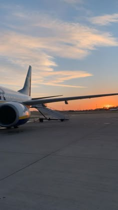 an airplane sitting on the tarmac at sunset