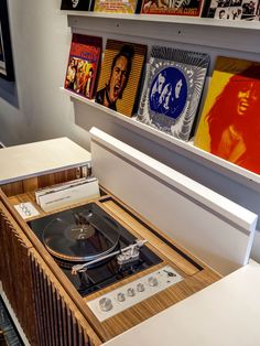 an old record player sitting on top of a wooden table in front of some posters