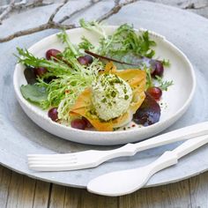 a white plate topped with salad next to a fork