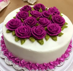 a white cake with purple flowers on top and happy anniversary written in the middle, sitting on a plate