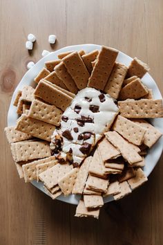 a white plate topped with crackers covered in ice cream and chocolate chips next to marshmallows