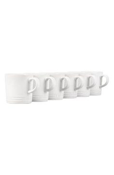 four white coffee mugs lined up in a row on top of eachother