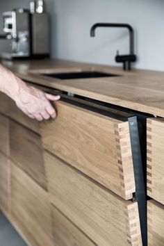 a person reaching for something on top of a wooden counter in front of a sink