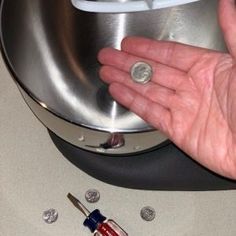 a person's hand holding a tiny coin in front of a machine