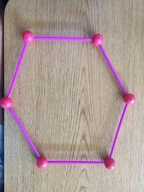 a wooden table topped with pink beads and a purple frame on it's side