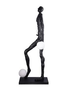 a black and white statue with two balls on it's feet, standing in front of a white background