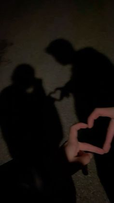 two people standing next to each other with their hands in the shape of a heart