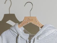 a wooden hanger with the word bride on it hanging from a white sweatshirt jacket