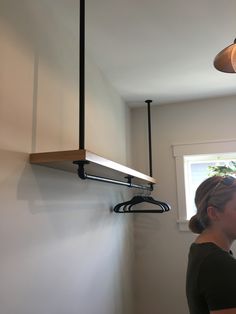 a woman standing in front of a window next to a wall mounted shelf with lights on it