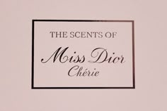 the scents of miss dior cherie is displayed on a pink background with black and white lettering