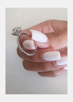 a woman's hand holding a ring with white acrylic nails