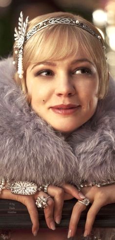 a woman wearing a fur collar and pearls on her head, posing for the camera