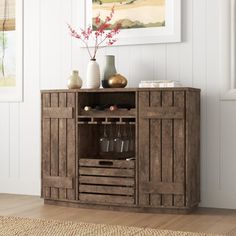 a wooden cabinet with wine glasses and vases on it in a living room area