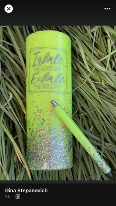 a green lighter with glitter on it and a pen in the grass next to it