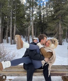 a man and woman sitting on a bench in the snow