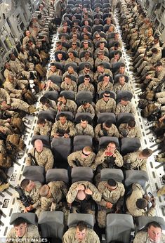 many soldiers are sitting on the back of an aircraft