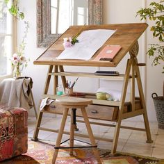 a wooden easel sitting on top of a table next to a window with flowers