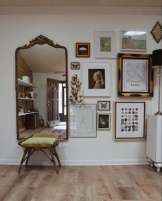 a room with pictures on the wall and a bench in front of a large mirror