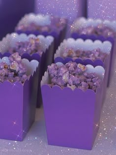 there are many purple bags that have popcorn in them and sparkles on the table