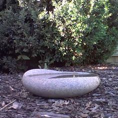 there is a rock with scissors in it on the ground near some bushes and trees