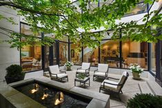 an outdoor living area with chairs, tables and water feature in the center surrounded by greenery