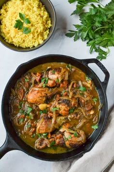 a skillet filled with chicken and rice next to a bowl of cilantro