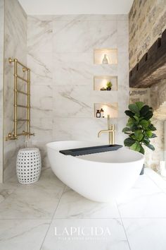 a white bath tub sitting in a bathroom next to a plant