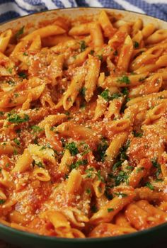 pasta with sauce and parsley in a green dish on a blue and white towel