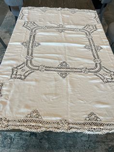 an old table cloth is sitting on top of a wooden table with chairs in the background