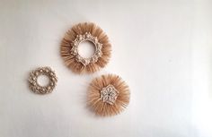 three pieces of art made out of straws on a white surface, including two rings and one ring