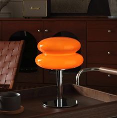 an orange chair sitting on top of a wooden table next to a cup and saucer