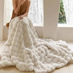 a woman sitting on the floor in a white blanket