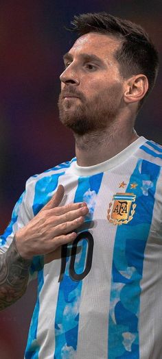 a man with tattoos on his arm and chest standing in front of a soccer ball