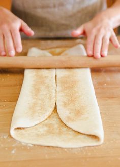 a person rolling out dough on top of a wooden table