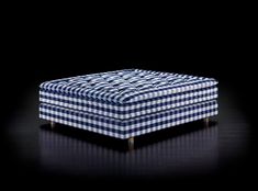 a blue and white checkered ottoman sitting on top of a black floor with dark background